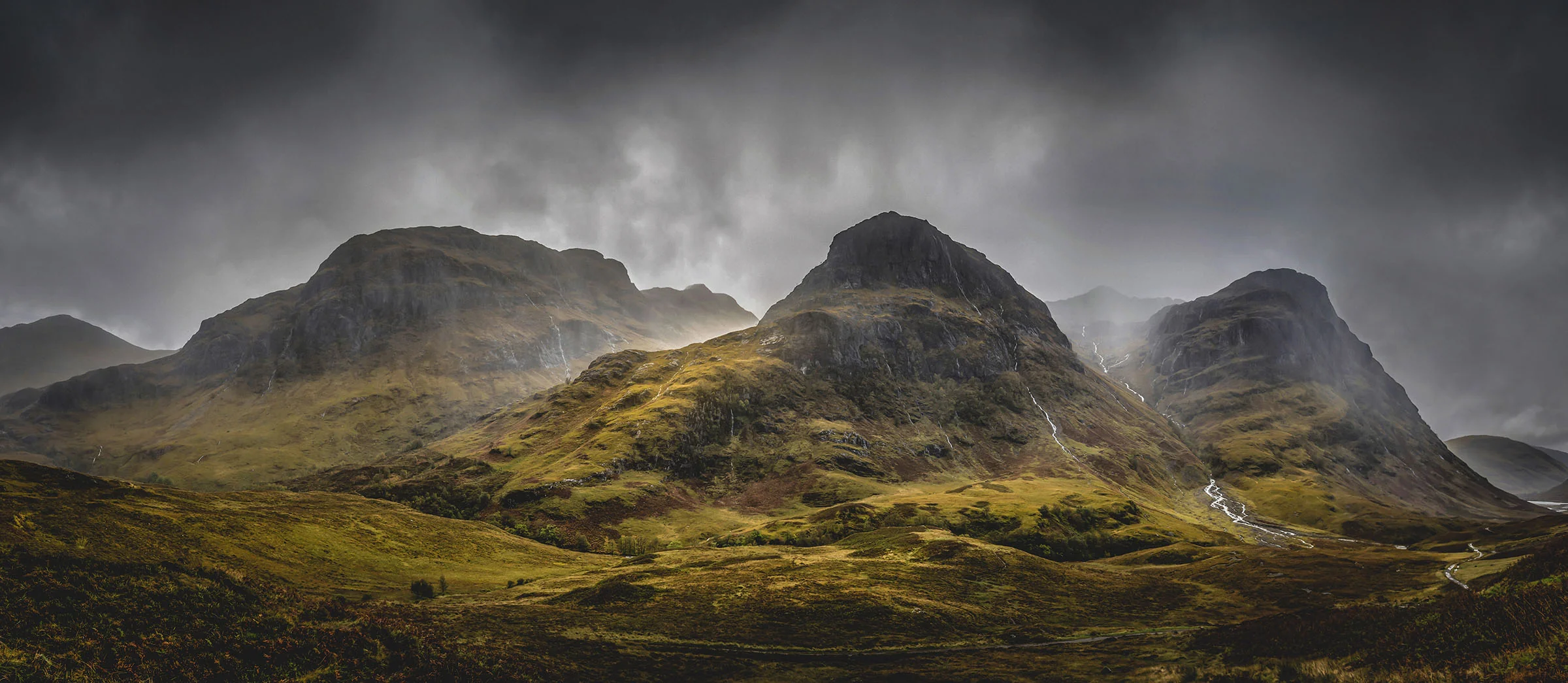 The Three Sisters mountains in Glen Coe beneath dark rain clouds