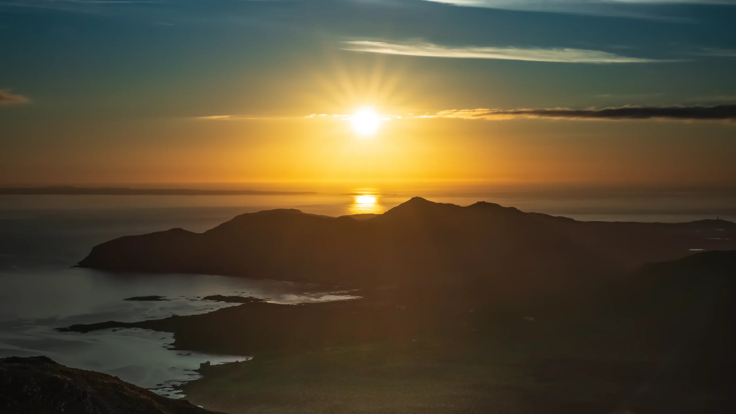Golden evening sunlight over the sea and the dark headlands of the Ardnamurchan peninsula
