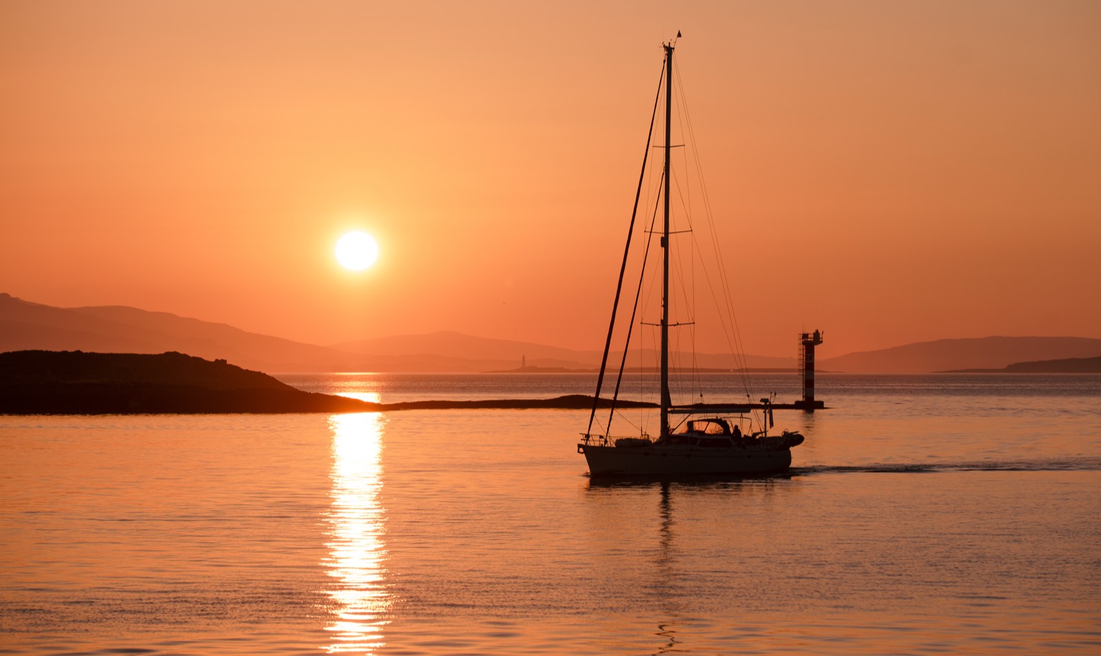 A sailing boat silhouetted against an orange sunset near Oban.